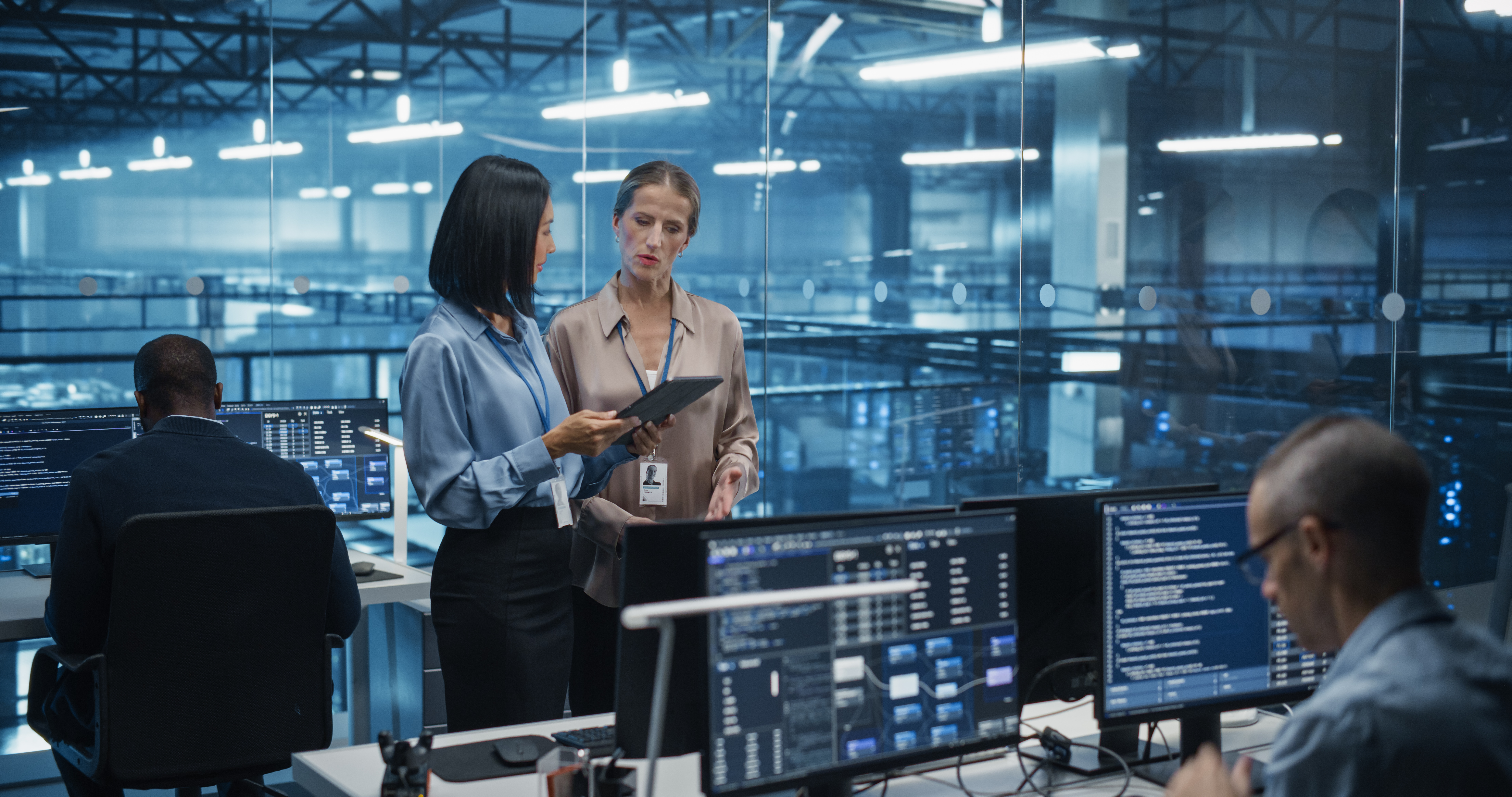 In a Modern Data Center, Caucasian Female Data Scientist and Asian Female AI Specialist Analyze Algorithms on a Tablet Computer. Specialists Exploring Optimizations for Processing Large Datasets